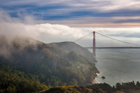 Golden Gate Bridge viewed from the Marin Headlands with coastal cliffs, fog, and ocean below