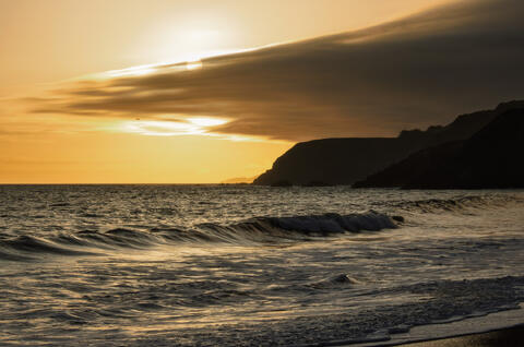 Rodeo Beach in Marin Headlands with ocean waves at sunset and low clouds stretching over the coastline