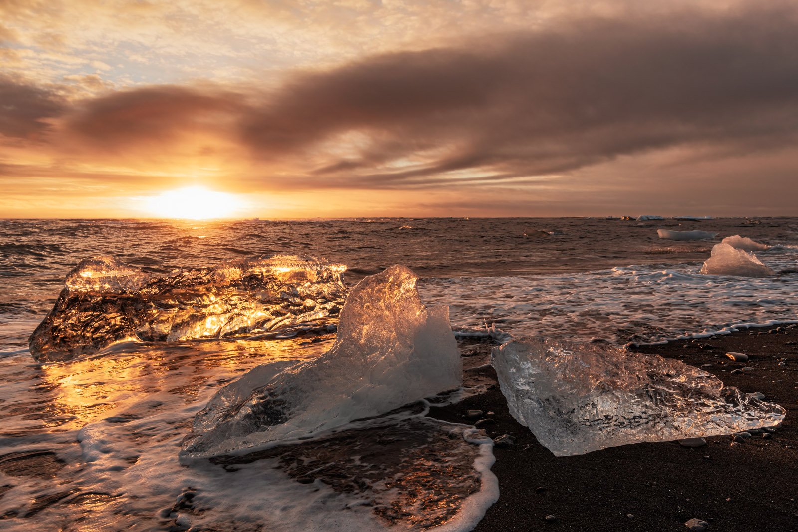 Glistening ice chunks at sunset on Diamond Beach in Southeast Iceland.