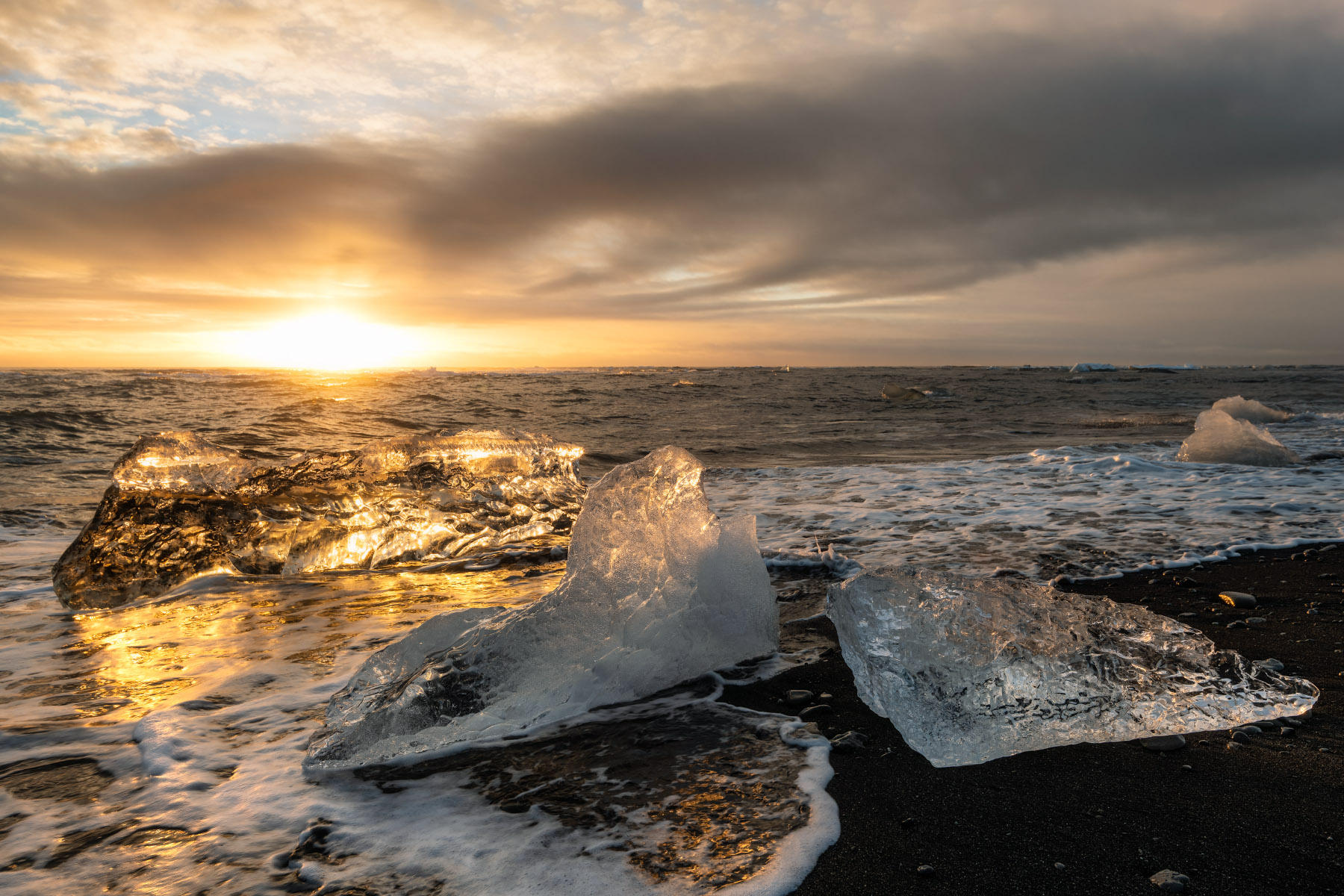 Glistening ice chunks at sunset on Diamond Beach in Southeast Iceland.
