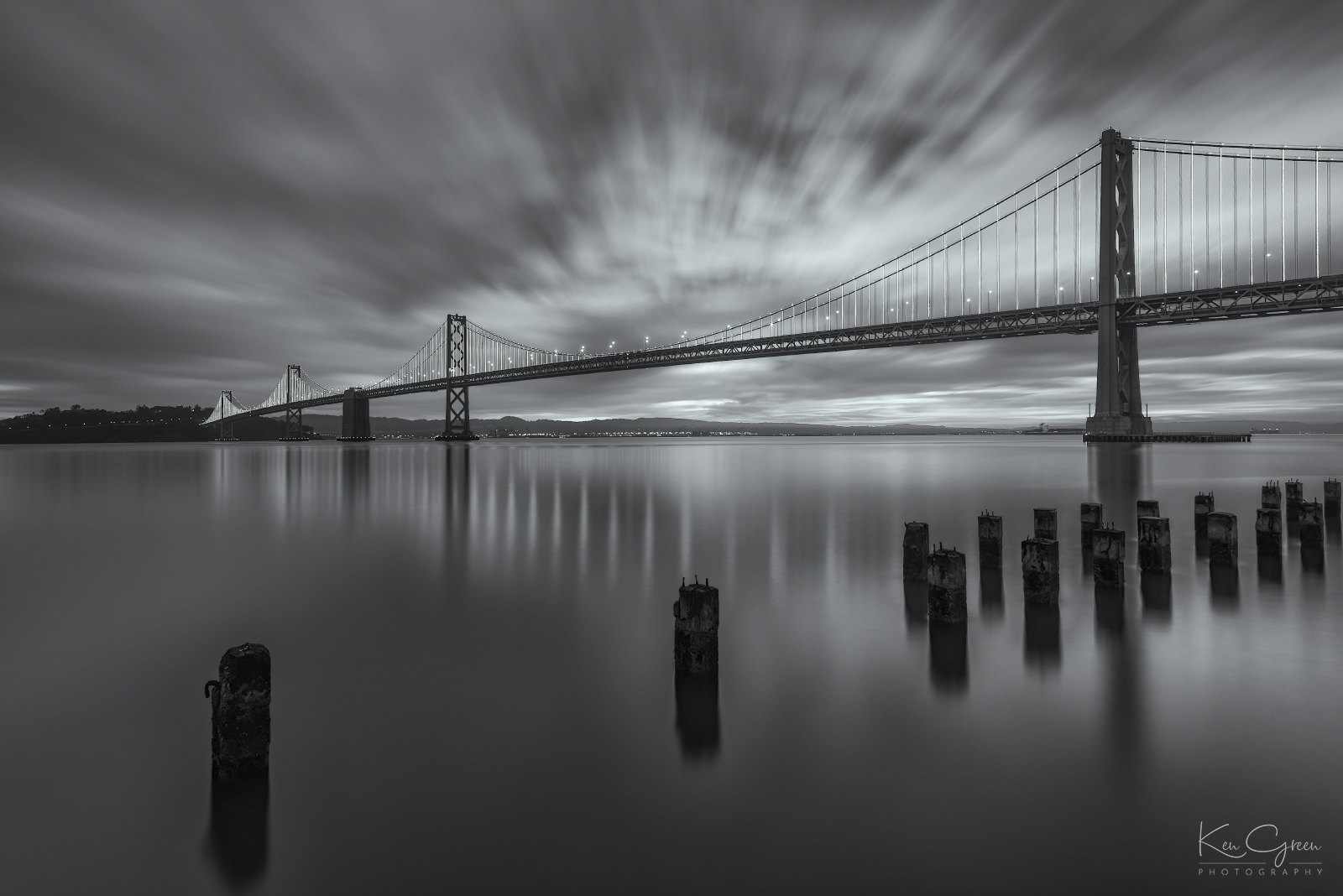 Monochromatic, long exposure sunrise photo of the San Francisco-Oakland bay bridge.